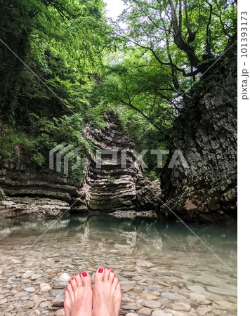 Female red pedicure feet refreshing in the river clear water of mountain stream, on the background cliff Female red pedicure feet refreshing in the river clear water of mountain stream, on the background cliff 101393173