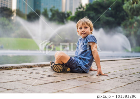 Boy on background of Fountain on the lake in the evening, near by Twin Towers with city on background. Kuala Lumpur, Malaysia Boy on background of Fountain on the lake in the evening, near by Twin Towers with city on background. Kuala Lumpur, Malaysia 101393290