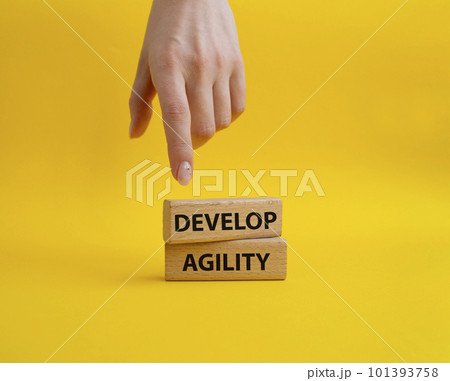 Develop agility symbol. Concept word Develop agility on wooden blocks. Beautiful yellow background. Businessman hand. Business and Develop agility concept. Copy space Develop agility symbol. Concept word Develop agility on wooden blocks. Beautiful yellow background. Businessman hand. Business and Develop agility concept. Copy space 101393758