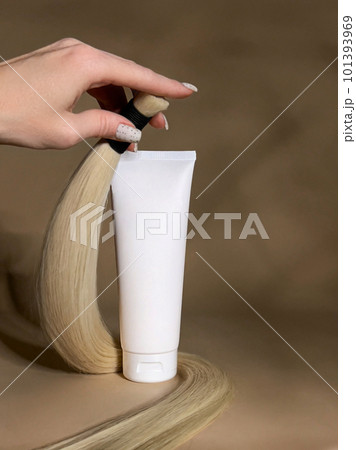 A strand of natural light hair for extensions with a bottle of care product. A strand of natural light hair for extensions with a bottle of care product. 101393969