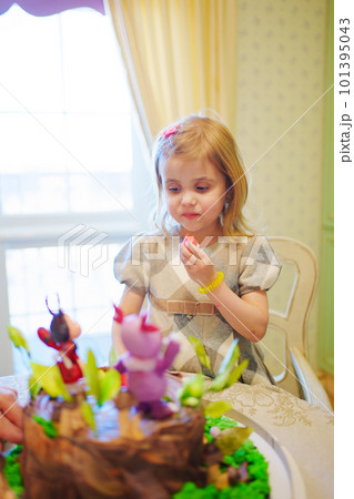 little girl with a large cake with figures of fairy-tale characters little girl with a large cake with figures of fairy-tale characters 101395043
