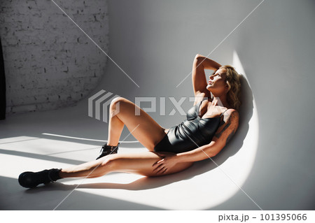 a portrait of a sexy blonde with tattoos in a leather swimsuit and boots. a portrait of a sexy blonde with tattoos in a leather swimsuit and boots. 101395066
