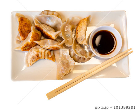 Plate of fried Chinese dumplings and bowl of soy sauce with chopsticks Plate of fried Chinese dumplings and bowl of soy sauce with chopsticks 101399281