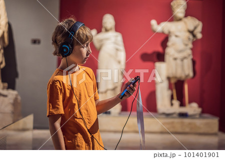 Boy looking at sculptures and listening to audio guide at museum exhibition Boy looking at sculptures and listening to audio guide at museum exhibition 101401901