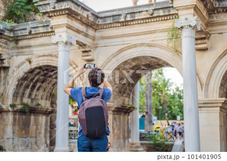 Happy male tourist traveler discover interesting places and popular attractions and walks in the old city of Antalya. Hadrian Kapisi turkey landmark city history. Popular tourist attraction - ancient 101401905