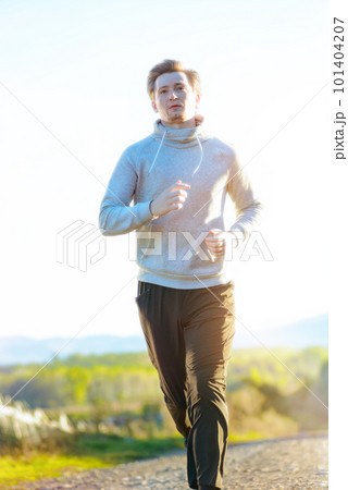 Man jogging in rural nature at beautiful summer day. Sport fitness model caucasian ethnicity training outdoor. 101404207