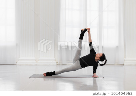 Charming young woman doing vertical splits during yoga class in a cozy gym. The concept of flexibility, leg and back muscle tone, balance and concentration 101404962