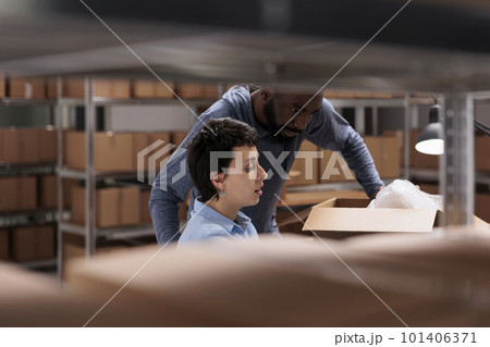 Storehouse team looking at transportation logistics on laptop computer before start working at package delivery, discussing client shipping order details. Diverse employee working in warehouse 101406371