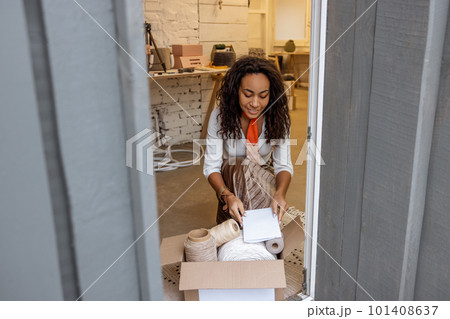 Long-haired young woman packing boxes with ordered products for delivery 101408637