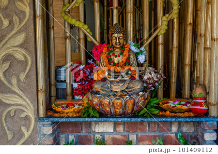 Bronze buddha statue sitting in meditation with flower decorations for festival ceremony.  101409112