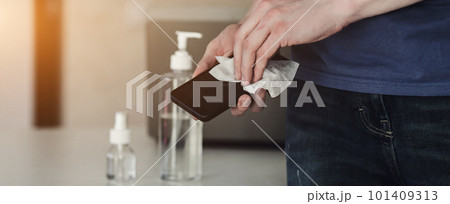 Man disinfecting phone with antiseptic wet wipe Man disinfecting phone with antiseptic wet wipe 101409313
