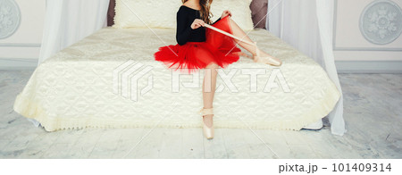 Girl in a red skirt sits on the bed Girl in a red skirt sits on the bed 101409314