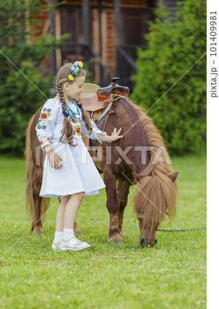 young girl in Ukrainian national dress strokes a pony young girl in Ukrainian national dress strokes a pony 101409981