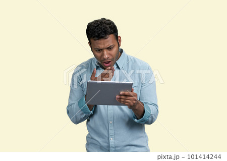 South asian man with expression of bewilderment and surprise holding tablet pc. Puzzled indian guy on white background. South asian man with expression of bewilderment and surprise holding tablet pc. Puzzled indian guy on white background. 101414244