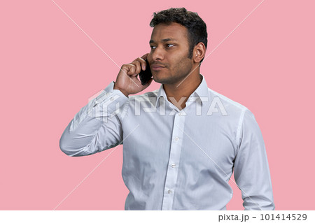 Portrait of indian man talking on his smartphone. Isolated on pink background. 101414529