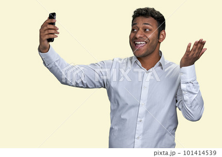 Cheerful indian business man smiling as talking to friend via mobile phone. Waving hand saying hi or hello. Isolated on white background. 101414539