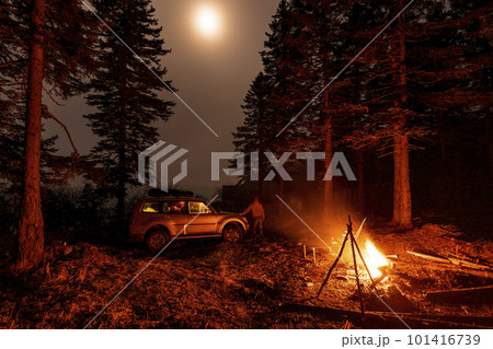A man stands at his car in a tourist camp in a fir forest near the sea. A man stands at his car in a tourist camp in a fir forest near the sea. 101416739