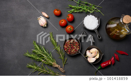 Miniature pans with spices, salt, black pepper and fragrant pepper, a sprig of rosemary on a black table. Spices for cooking Miniature pans with spices, salt, black pepper and fragrant pepper, a sprig of rosemary on a black table. Spices for cooking 101418859