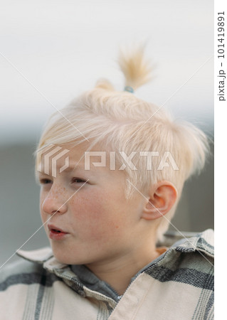 Close up of a blonde boy face with cute hairstyle with tail on top, explaining something, boy seriously talking to his friend Close up of a blonde boy face with cute hairstyle with tail on top, explaining something, boy seriously talking to his friend 101419891