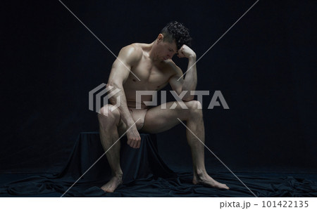 Portrait of serious, thoughtful, mature man sitting, posing shirtless in underwear against black studio background 101422135