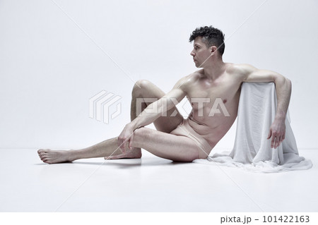 Portrait of handsome mature man posing shirtless in underwear against white studio background with fabric elements. Muscular body 101422163