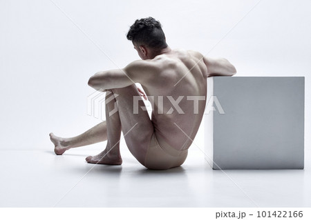 Man with relief, muscular, strong body shape sitting, posing shirtless in underwear against white studio background. Back view 101422166