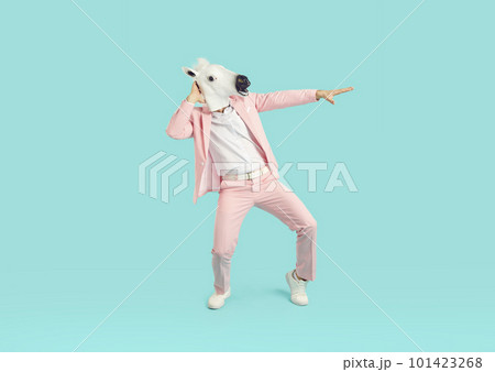Funny man wearing bright pink suit in animal head horse mask dancing on studio blue background. 101423268