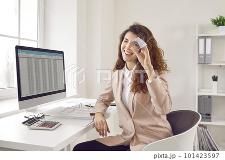 Happy, smiling woman accountant sitting in the office and looking through the hole in a paper roll 101423597