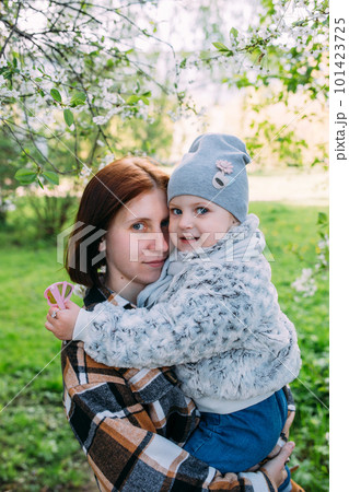Young woman with her daughter in nature admires white flowering of spring trees Young woman with her daughter in nature admires white flowering of spring trees 101423725