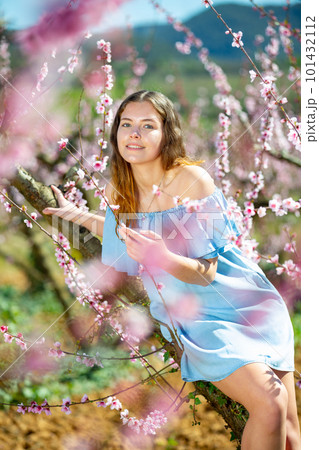 Portrait of an attractive girl in blue dress in blooming peach garden Portrait of an attractive girl in blue dress in blooming peach garden 101432112