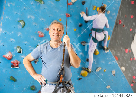 Portrait of sports man in climbing equipment on background of climbing wall Portrait of sports man in climbing equipment on background of climbing wall 101432327