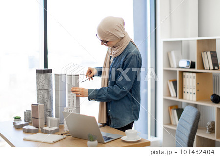 Lady using compass and laptop in architecture office 101432404