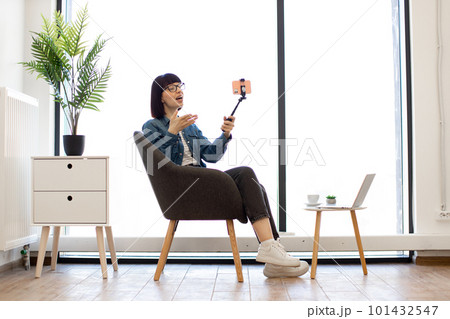 Female taking selfie with v-sign using phone stick in office 101432547