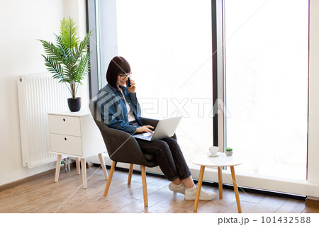 Business lady talking on phone while using laptop in office Business lady talking on phone while using laptop in office 101432588
