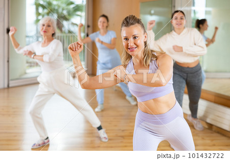 Cheerful energetic female dancers of different ages learning new dancing steps in modern fitness class Cheerful energetic female dancers of different ages learning new dancing steps in modern fitness class 101432722