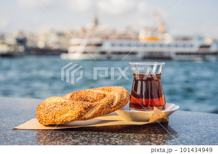A glass of Turkish tea and bagel Simit against golden horn bay in Istanbul, Turkey. Turkiye 101434949