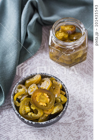 Spicy mexican pickled jalapeno peppers in bowl and glass jar vertical view Spicy mexican pickled jalapeno peppers in bowl and glass jar vertical view 101435543