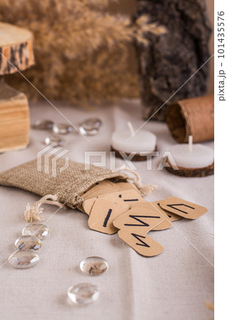 Handmade cardboard Scandinavian runes in a bag on a divination table vertical view 101435576