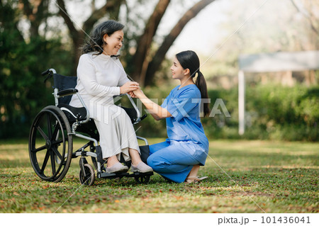 Elderly asian senior woman on wheelchair with Asian careful caregiver. Nursing home hospital garden concept. in sun light Elderly asian senior woman on wheelchair with Asian careful caregiver. Nursing home hospital garden concept. in sun light 101436041