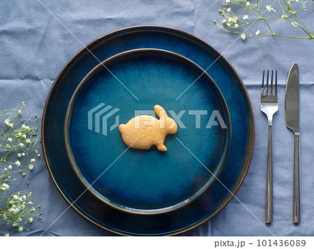 Festive Easter table setting with cookie and flowers on blue background 101436089