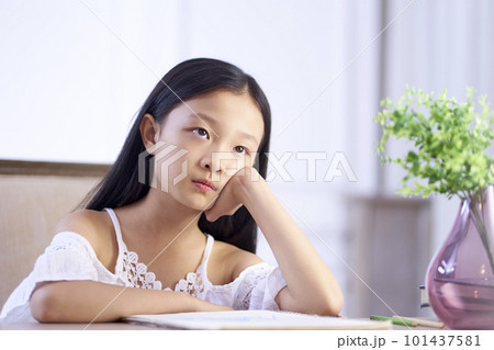 beautiful little asian girl with long black hair sitting at desk in her room looking up thinking beautiful little asian girl with long black hair sitting at desk in her room looking up thinking 101437581