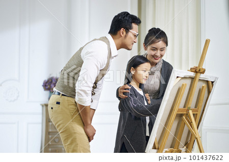 little asian girl making a painting with parents watching and helping little asian girl making a painting with parents watching and helping 101437622
