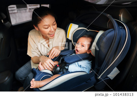 mother take care her newborn baby in car seat. play and talking with child 101438313