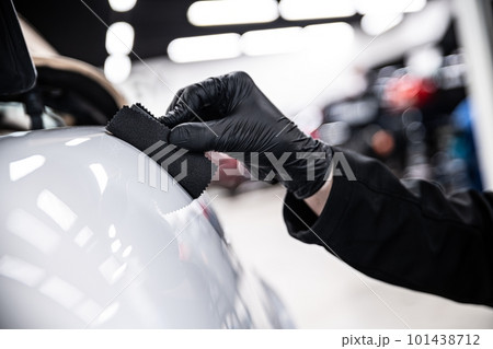 Employee of a car detailing studio or a car wash applies a ceramic coating 101438712