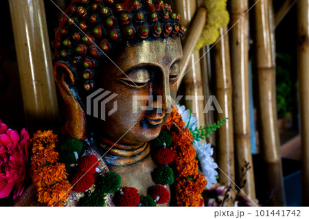 Close up of bronze buddha statue sitting in meditation with flower decorations for festival ceremony. Close up of bronze buddha statue sitting in meditation with flower decorations for festival ceremony. 101441742