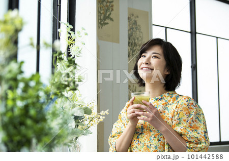 笑顔でグリーンスムージーを飲む若い女性 101442588