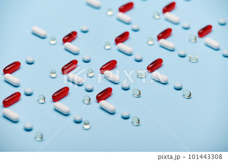 Medical background with red gelatin translucent capsules with essential oils, Omega 3 or fat-soluble vitamins and pharmaceutical pills laid out in pattern on blue surface. Pharma industry and business Medical background with red gelatin translucent capsules with essential oils, Omega 3 or fat-soluble vitamins and pharmaceutical pills laid out in pattern on blue surface. Pharma industry and business 101443308