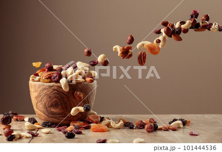 The mix of nuts and raisins in a wooden bowl. The mix of nuts and raisins in a wooden bowl. 101444536