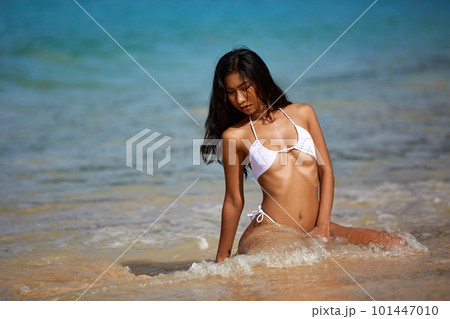 Beautiful asian girl in white bikini posing at the tropical beach Beautiful asian girl in white bikini posing at the tropical beach 101447010