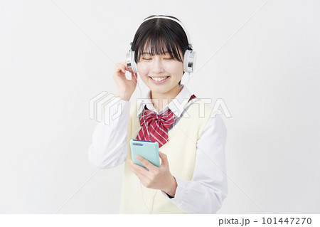 ヘッドホンをしてスマートフォンで音楽を聴く女子高生 白背景 ヘッドホンをしてスマートフォンで音楽を聴く女子高生 白背景 101447270